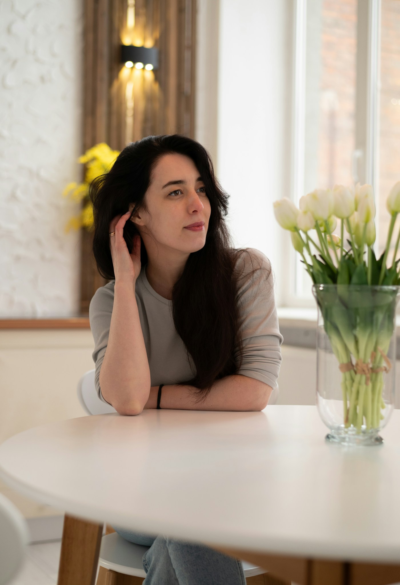 Linden Ashby seated at a table in a sunlit room beside white tulips