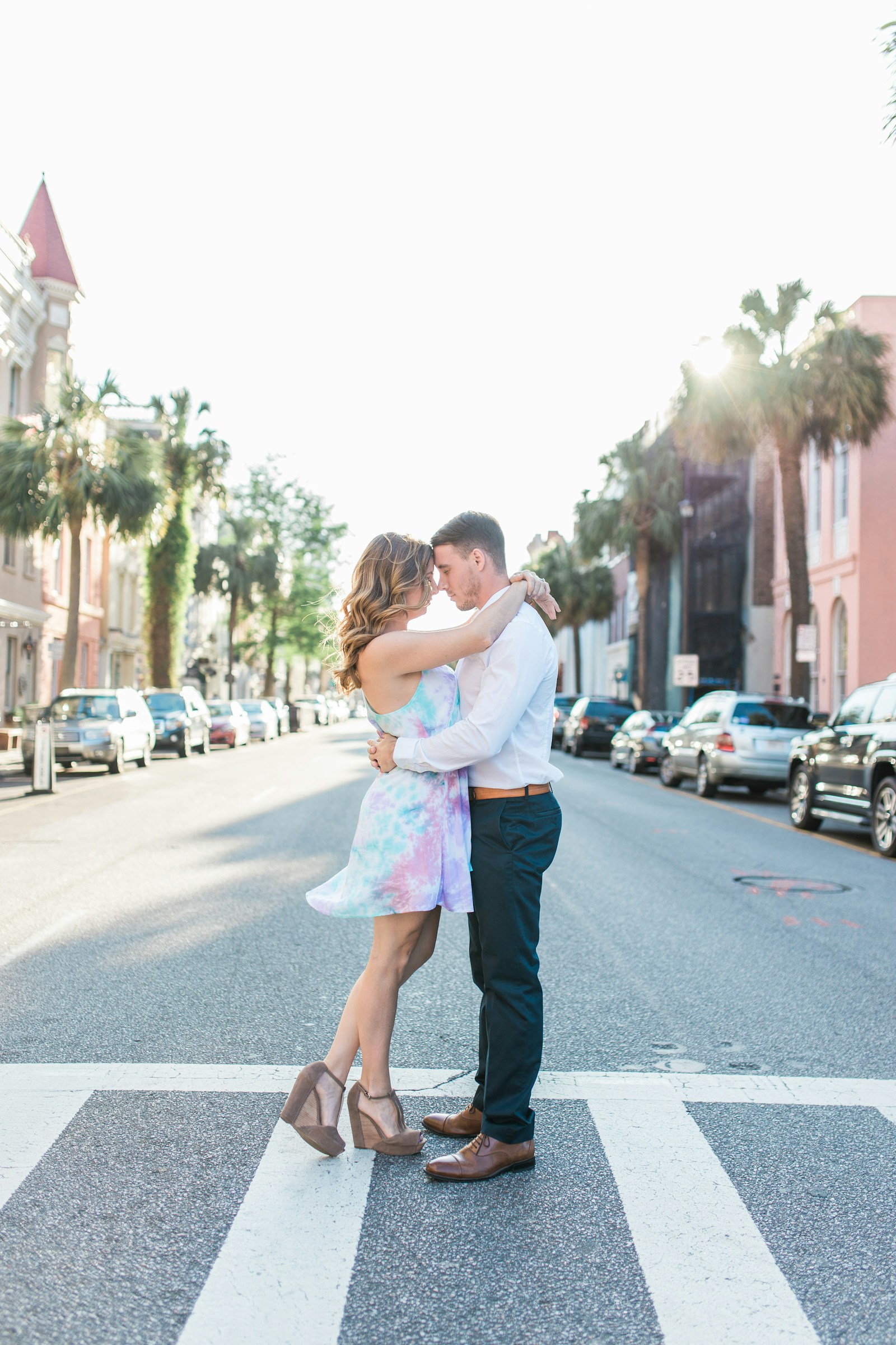 Couple embracing on a sunlit Charleston street lined with palms